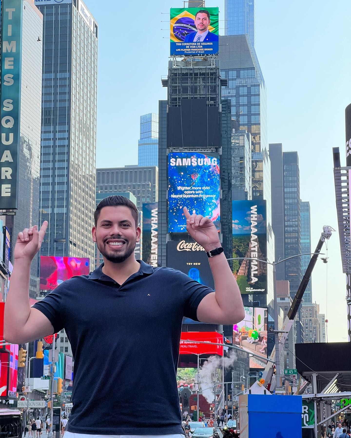 Taylor Miranda na Times Square, Nova York, ao lado do painel da TRM Corretora / Prudential